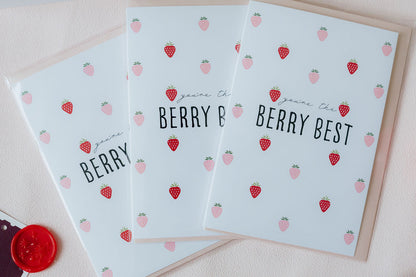 Three light blue greeting cards with strawberry patterns and text on a beige surface.