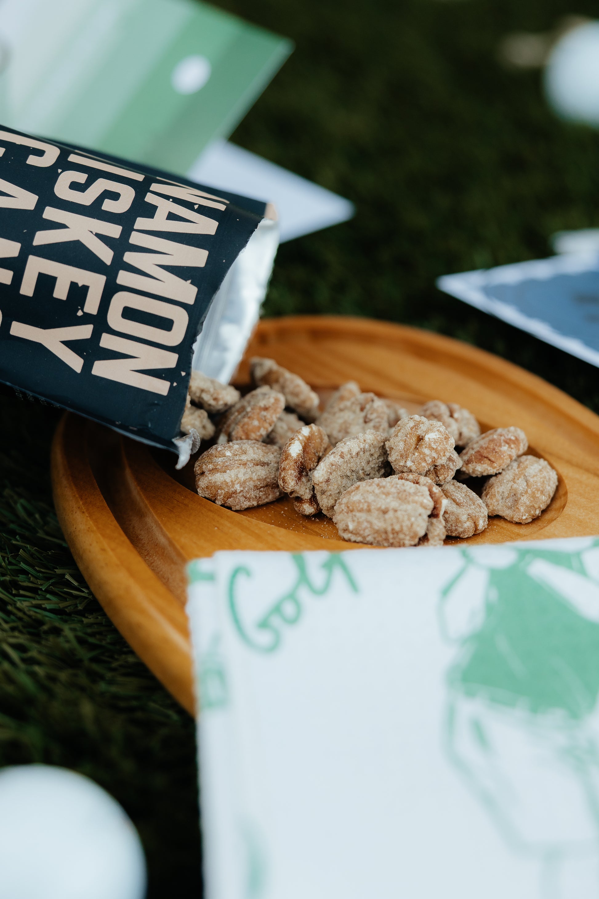 Nuts on a wooden plate with a package labeled Cinnamon Whiskey pecans in the background.