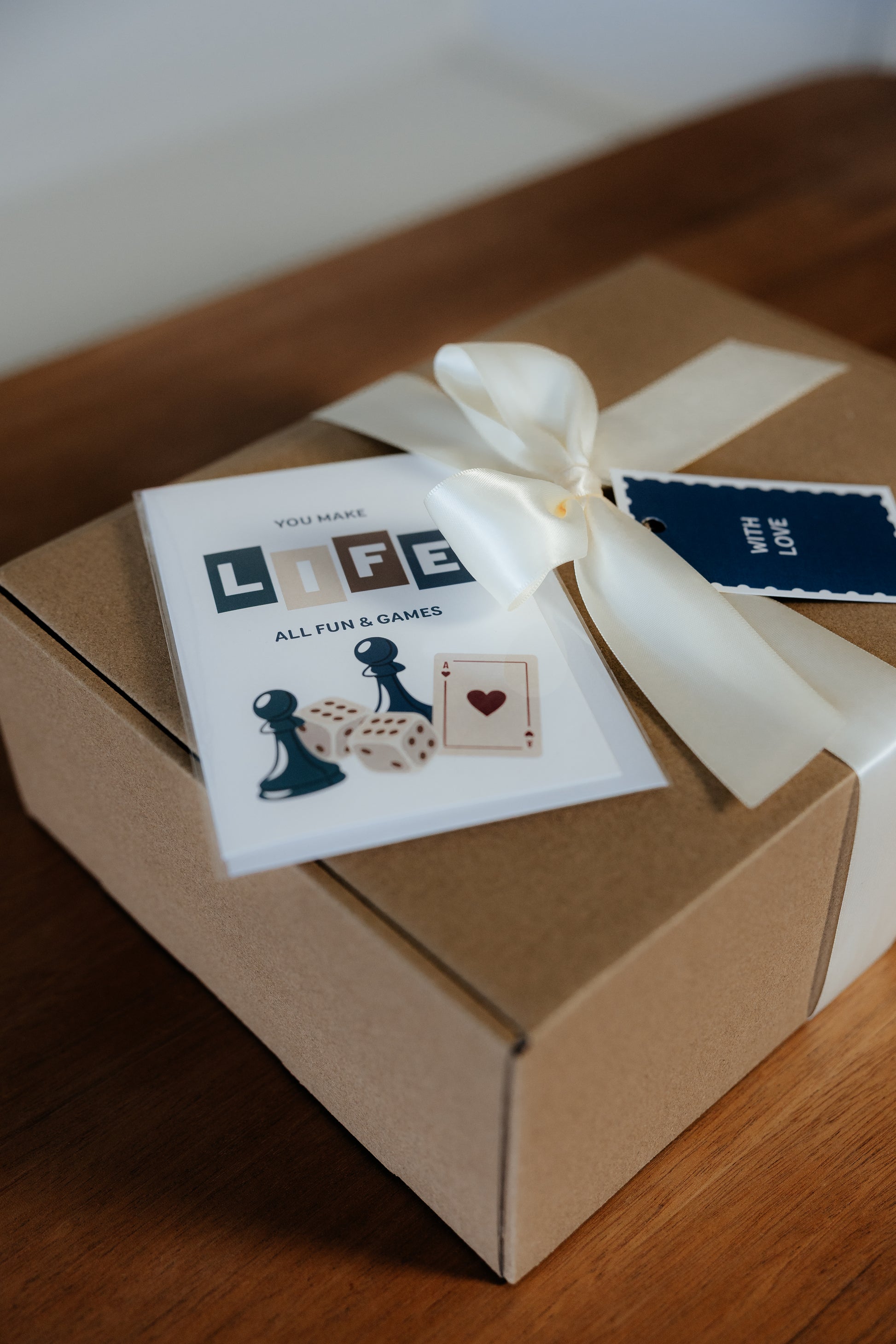 Gift box with a white ribbon and a card on a wooden surface