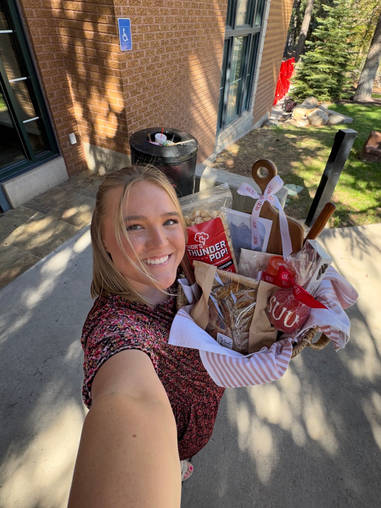 Paige holding a large gift basket outside a building