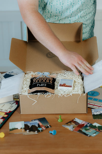 Person opening a box with game-themed items on a wooden table