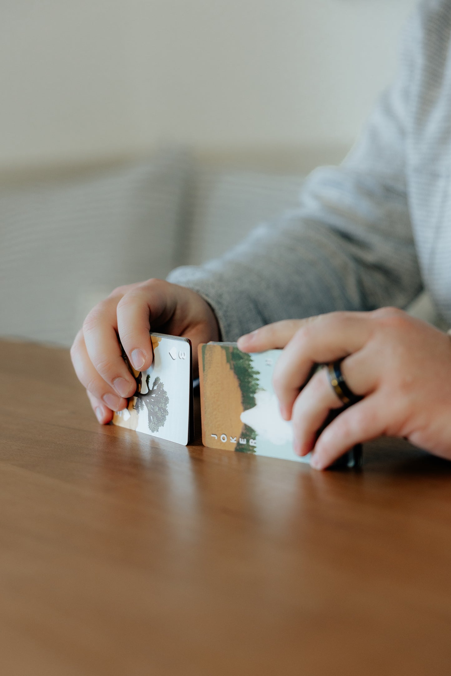 Person shuffling cards with nature-themed designs on a wooden surface.